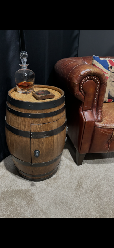 Whiskey barrel end table with crystal decanter beside a leather armchair